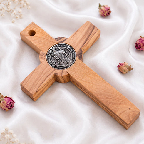 Back of a handmade olive wood cross with a blue St. Benedict medallion on a white background.