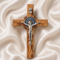 Handcrafted olive wood cross with St. Benedict medallion and silver crucifix on a white cloth