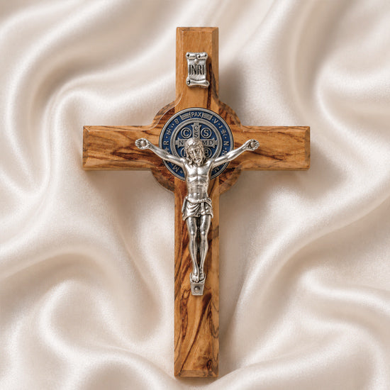 Handcrafted olive wood cross with St. Benedict medallion and silver crucifix on a white cloth