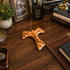 Wooden Tau cross on a wooden desk with motivational items and decor.