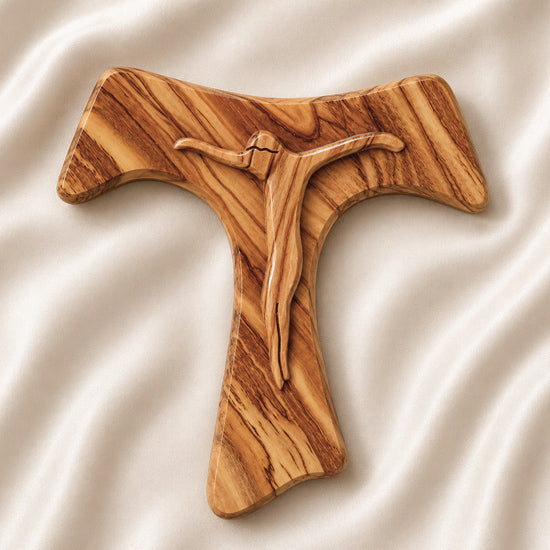 Frontal image of a handmade olive wood tau cross, also known as Saint Anthony's Cross, with modern crucifix design displayed on a white background with petals.