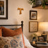 Cozy bedroom with a Tau cross, bed, pillows, and decorative items on a nightstand.