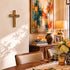 Dining room with wooden table, chairs, and decorative items including a cross and abstract painting.