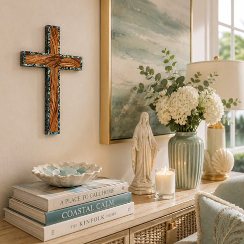 Decorative setting with books, statue, candle, and flowers on a console table.