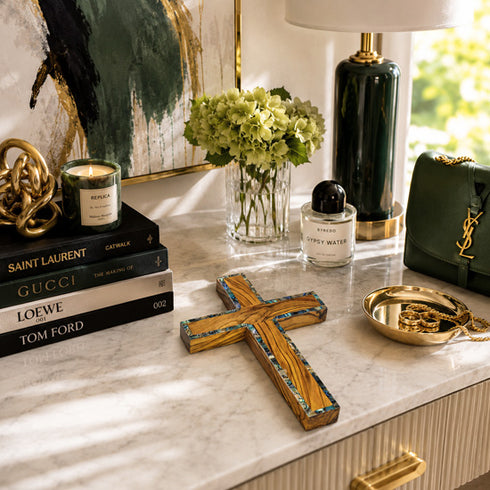 Decorative items on a marble surface including books, a cross, and a handbag.