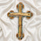 A handcrafted olive wood Eastern cross with mother-of-pearl inlays. Set against a white fluffy background.