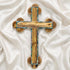 A handcrafted olive wood Eastern cross with mother-of-pearl inlays. Set against a white fluffy background.