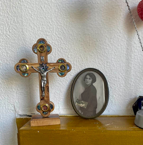 Medium olive wood eastern cross with nacre, crucifix and Four Holy Elements standing on a table next to a photograph.