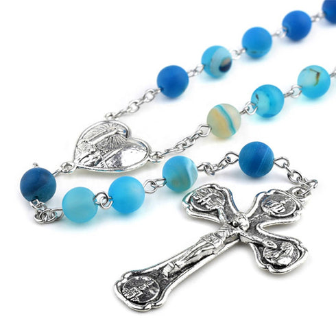 Blue rosary with silver cross and heart charm on a white background