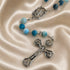 A rosary with blue and light blue marbled beads, metal crucifix on a beige satin fabric background.