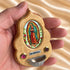 Hand holding an Our Lady of Guadalupe olive wood holy water font, showing its compact size and details