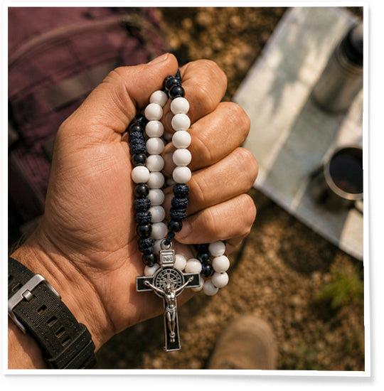 Hand holding a rosary with a blurred outdoor background