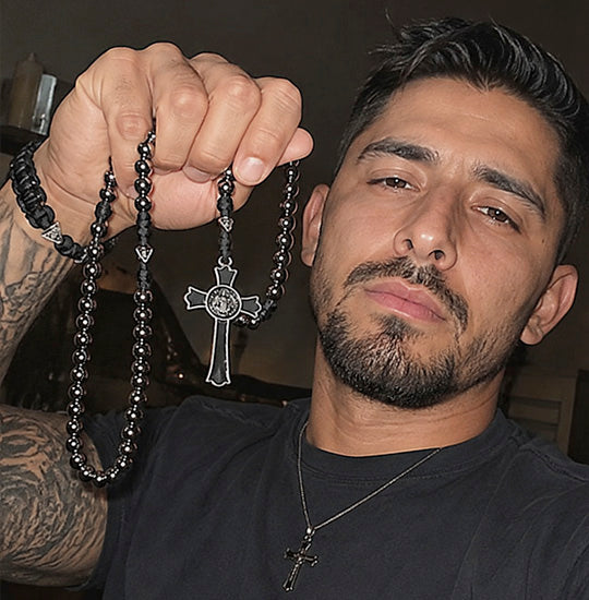 Man holding a black rosary with a cross pendant