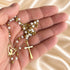 White pearl Catholic rosary with gold-tone chain and crucifix shown from an alternate angle