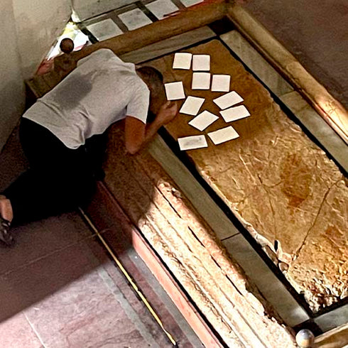 A person praying and placing a prayer notes on the Stone of Anointing inside the Church of the Holy Sepulchre.