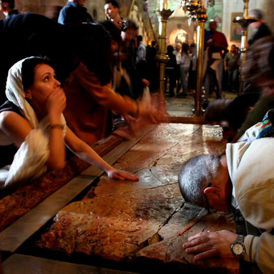 Pilgrims touching and kissing the Stone of Unction within the Church of the Holy Sepulchre.