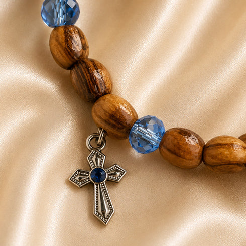 Olive wood bracelet close-up with blue crystal beads and silver cross charm