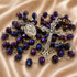 A rosary with dark iridescent beads, a silver-tone crucifix, and a medallion, on a beige satin fabric background.