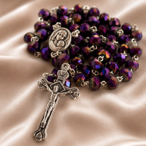 A rosary with purple and violet iridescent beads, a silver-toned medal of the Virgin Mary, and a silver-toned crucifix.