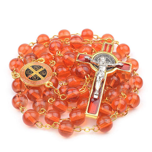 Red glass bead rosary with gold accents and St Benedict crucifix on a white background.