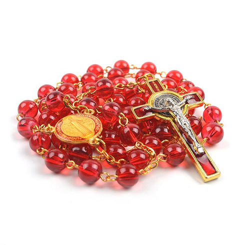 Red glass bead St. Benedict rosary with gold accents and a crucifix on a white background.
