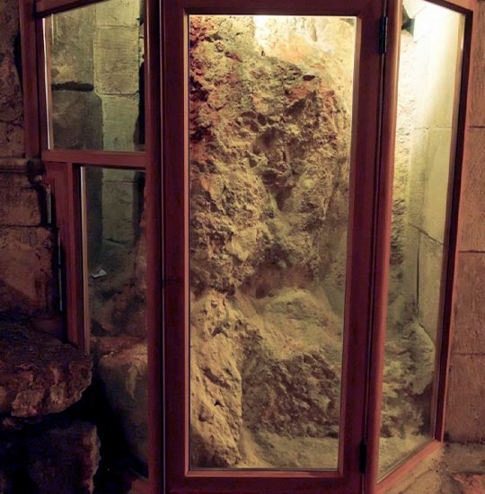 The rock of Calvary behind protective glass near the entrance to the Chapel of Adam.