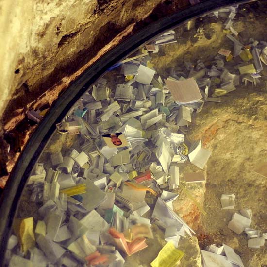 Paper prayers laid out at the Rock of Golgotha, with some written in different colors.