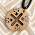Close-up of round wooden Jerusalem cross pendant on black cord with gold clasp