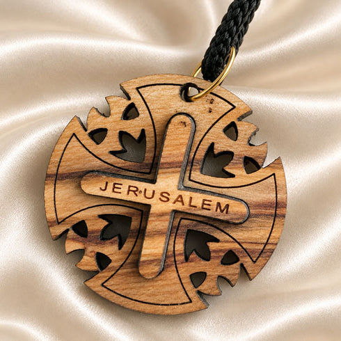 Close-up of round wooden Jerusalem cross pendant with black braided cord loop