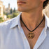 Round wooden pendant with Jerusalem cross on black cord, worn on neckline