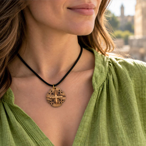 Round wooden pendant necklace with Jerusalem cross on black cord, worn at collar