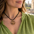 Round wooden pendant necklace with Jerusalem cross on black cord, worn at collar