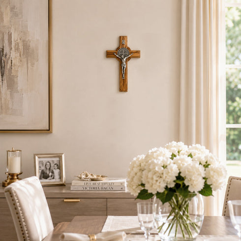 Dining room with a cross on the wall, framed picture, and white flowers in a vase.