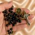 A close-up of a hand holding a black and gold rosary with a St Benedict medal and crucifix,on a satin fabric background.