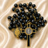 Black and gold rosary with polished black beads, a gold cross pendant, and a round medallion, on a cream satin fabric background.