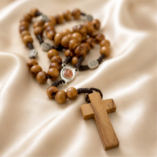 Wooden prayer beads with Soil medal and a wooden cross on a beige background
