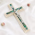 Image of a classic olive wood Latin cross featuring silver crucifix and Mother of Pearl inlay, surrounded by soft rose petals on a clean white surface.
