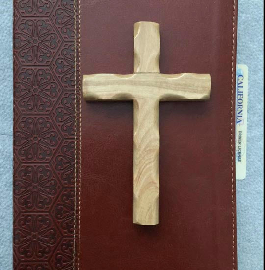 Olive wood Thorn cross laid on a closed red cover Bible