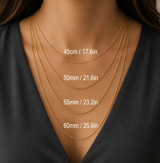Gold necklaces of different lengths displayed on a woman wearing a black top.