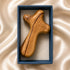 Olive wood comfort cross resting in an open blue gift box on ivory satin background.