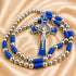 A silver beaded rosary with blue cord, a crucifix pendant, displayed on a satin fabric background.