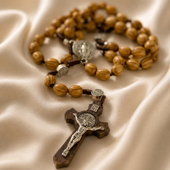 Wooden rosary with wooden and metal crucifix and a St Benedict medal on a beige cloth background