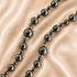 A close-up of a hematite rosary with large and small polished round beads separated by small silver spacer rings.