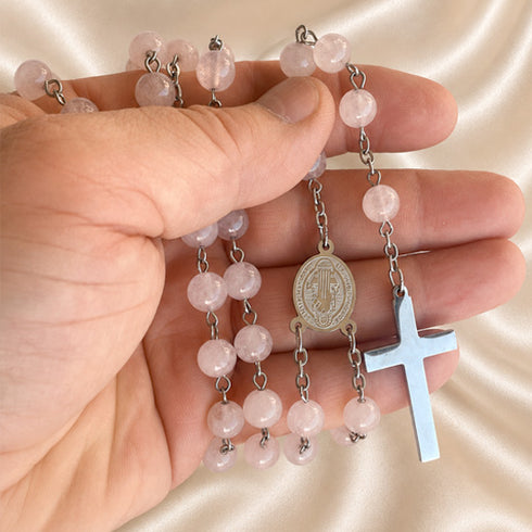 Pink jade rosary held in hand: St. Benedict medal and silver cross