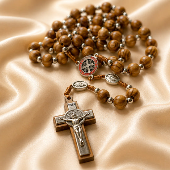 Olive wood prayer beads with St. Benedict medal centerpiece and silver crucifix on satin cloth.
