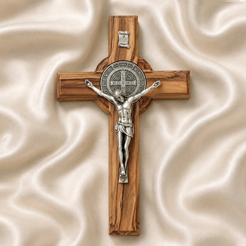 Wooden cross with silver Jesus figure on a beige fabric background