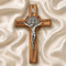 Wooden cross with silver Jesus figure on a beige fabric background