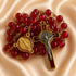 A red glass bead rosary with gold-tone metal links, a crucifix and a round St Benedict medal, on a beige fabric background.