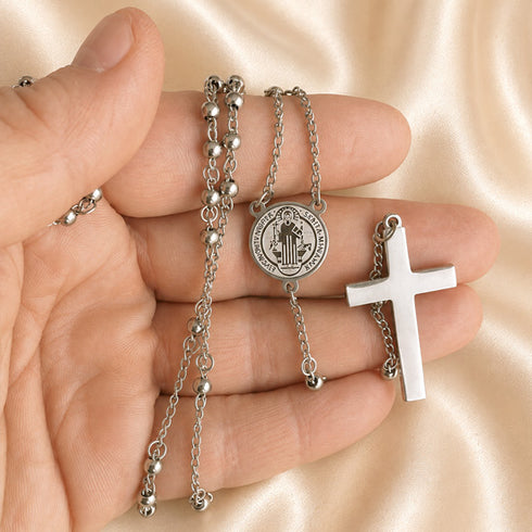 St. Benedict stainless steel rosary necklace held in hand with round medal and cross pendant