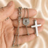 St. Benedict stainless steel rosary necklace held in hand with round medal and cross pendant